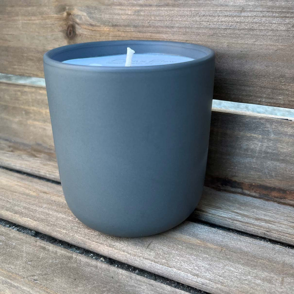 Fern x Flow 10oz hand-poured, 100% soy candle in a modern, charcoal-grey ceramic tumbler against a weathered wooden background.